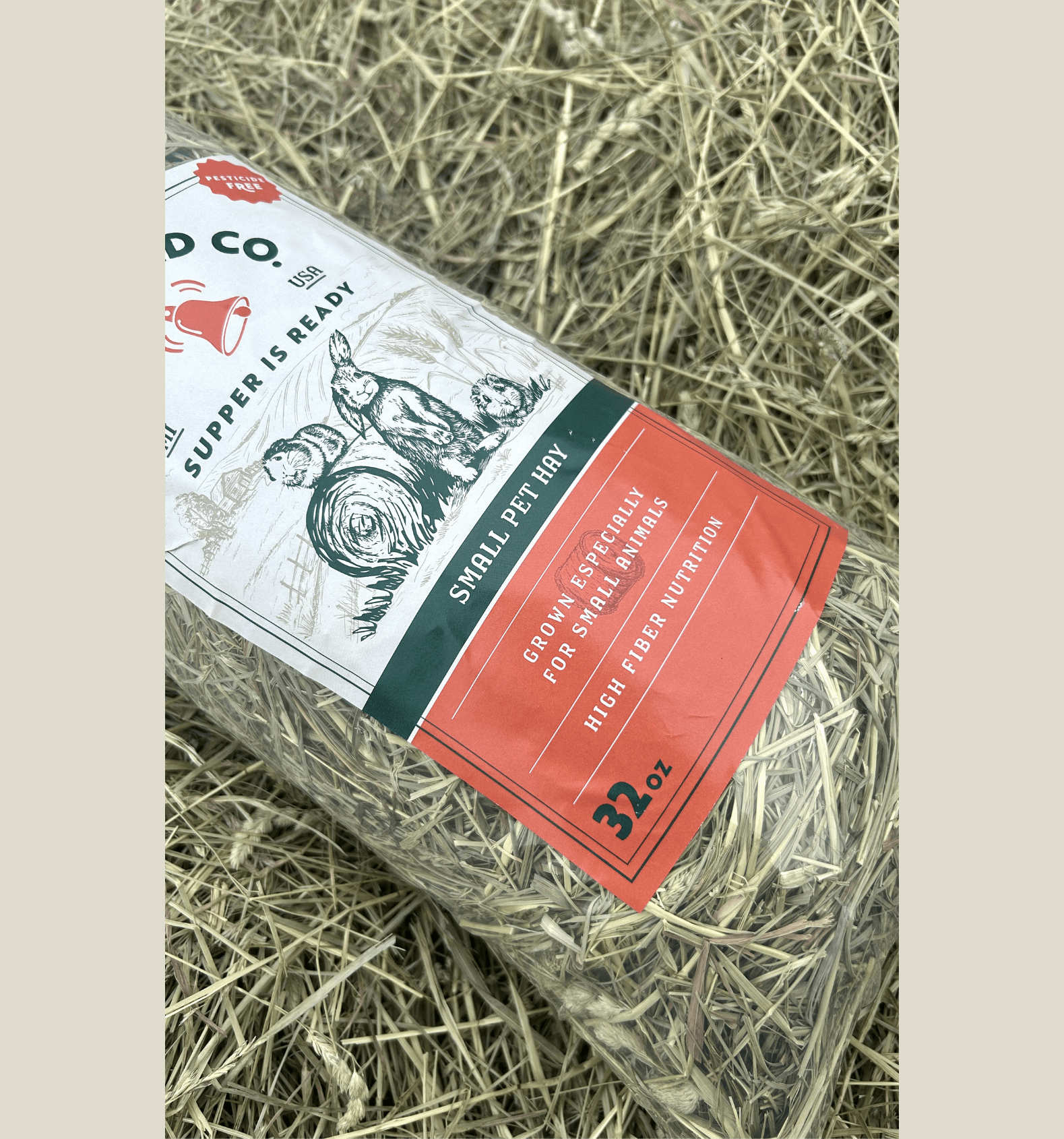 Pet hay package on a bed of hay with visible branding and text.