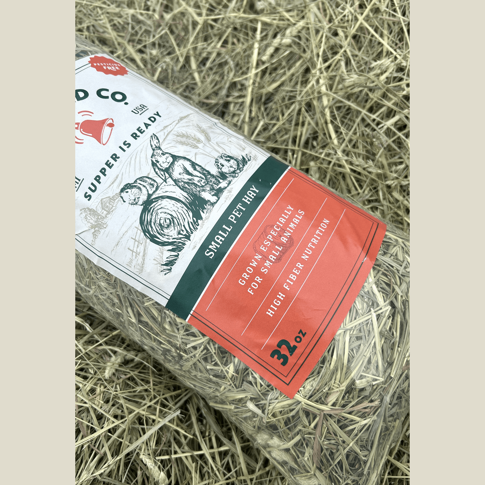 Pet hay package on a bed of hay with visible branding and text.